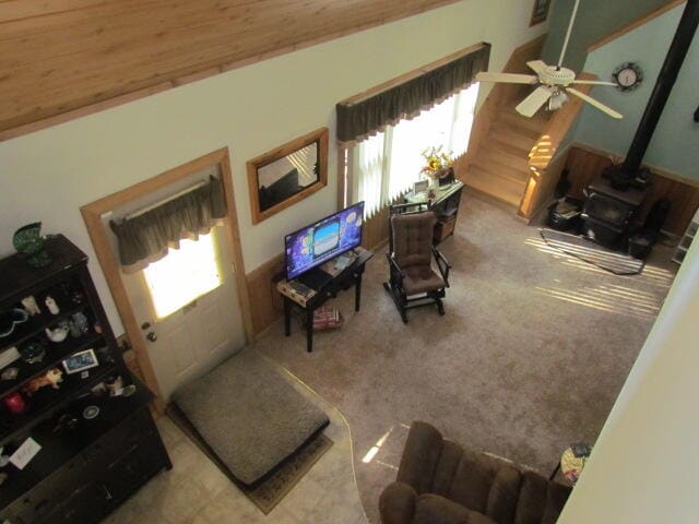 living room with a wood stove, wood ceiling, vaulted ceiling, and ceiling fan