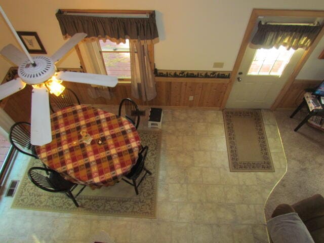 living room featuring wood walls, ceiling fan, and a healthy amount of sunlight