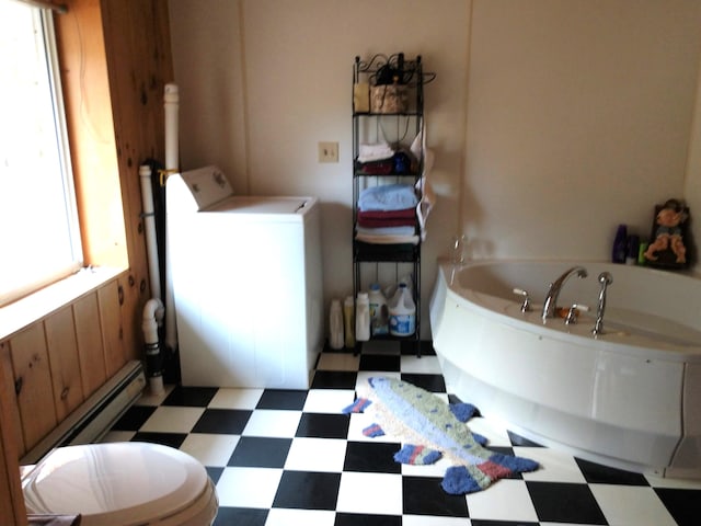 bathroom featuring tile patterned flooring, a bathing tub, a healthy amount of sunlight, and washer / dryer