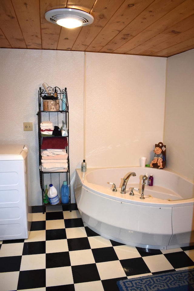 bathroom featuring washer / clothes dryer, wood ceiling, a tub to relax in, and tile patterned floors