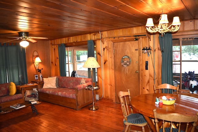 dining area with hardwood / wood-style floors, ceiling fan with notable chandelier, wooden ceiling, and wooden walls