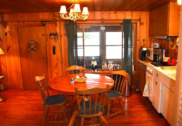 dining area featuring dark hardwood / wood-style floors, wood ceiling, wooden walls, and a chandelier