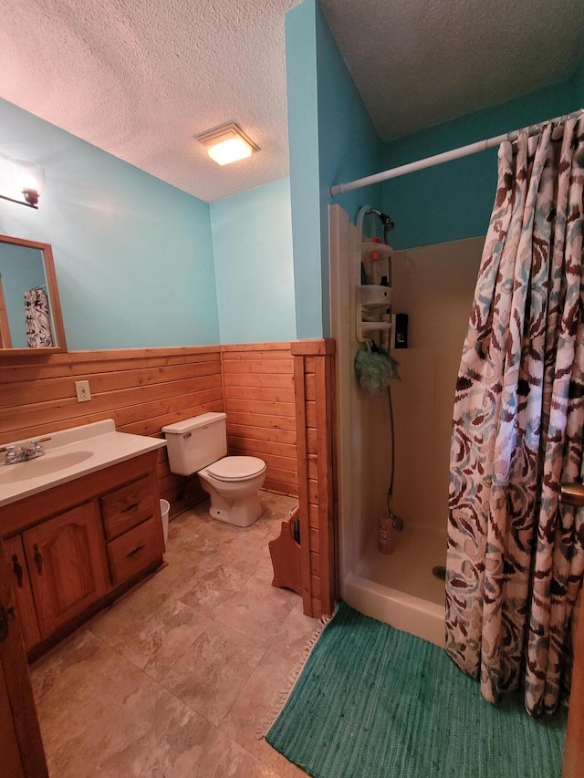 bathroom featuring vanity, tile patterned flooring, a textured ceiling, toilet, and walk in shower