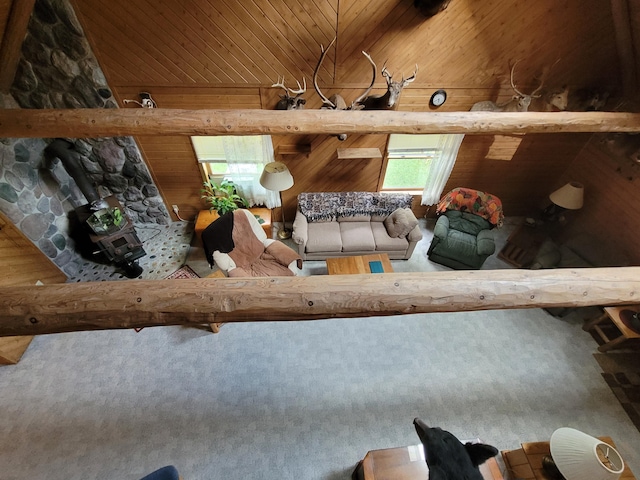 unfurnished living room with carpet, wooden walls, a wood stove, and wood ceiling