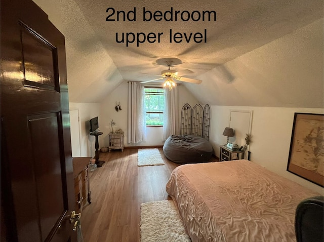 bedroom with ceiling fan, a textured ceiling, lofted ceiling, and wood-type flooring