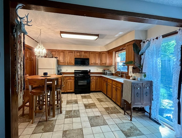 kitchen with light tile patterned floors, sink, pendant lighting, and black appliances