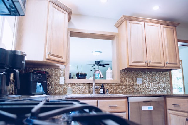 kitchen featuring backsplash, stainless steel dishwasher, light brown cabinetry, and ceiling fan