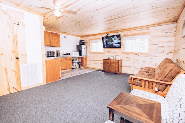 interior space with ceiling fan, wood walls, and wooden ceiling