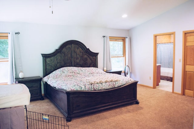 carpeted bedroom featuring vaulted ceiling and ensuite bathroom