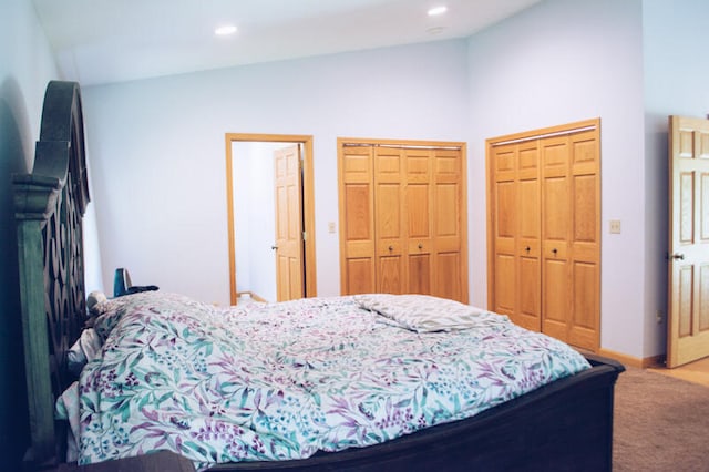 carpeted bedroom with vaulted ceiling and two closets