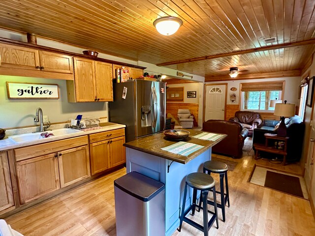 kitchen featuring light hardwood / wood-style flooring, wood ceiling, sink, stainless steel refrigerator with ice dispenser, and a breakfast bar area