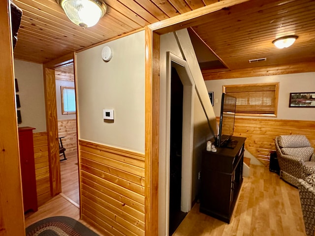 corridor featuring wood walls, wood ceiling, and light hardwood / wood-style floors