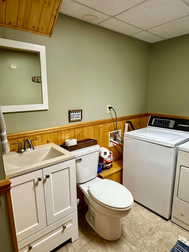 clothes washing area featuring wooden walls, independent washer and dryer, and sink