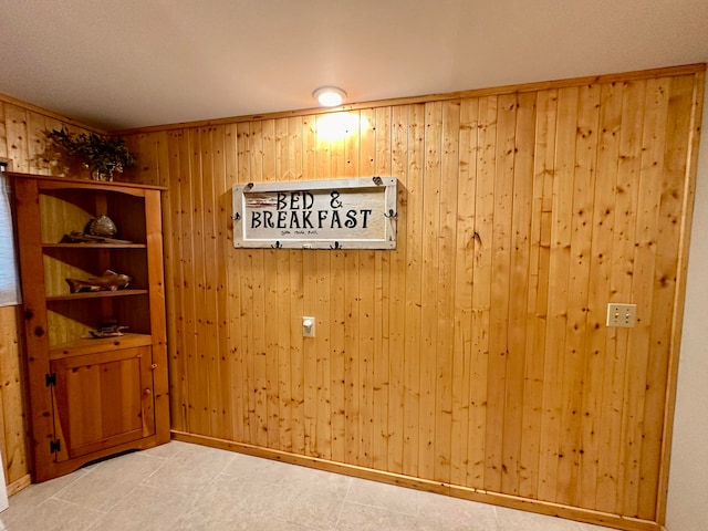 tiled spare room featuring wooden walls and ornamental molding