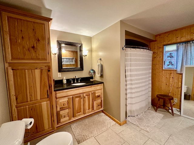 bathroom with vanity, toilet, wood walls, and tile patterned floors