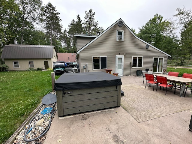 back of house with a hot tub, a lawn, and a patio area