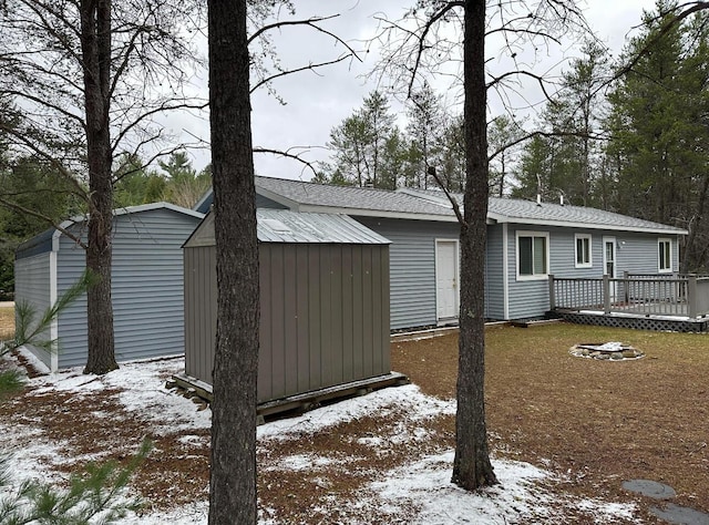 exterior space featuring a wooden deck, a storage unit, and an outbuilding