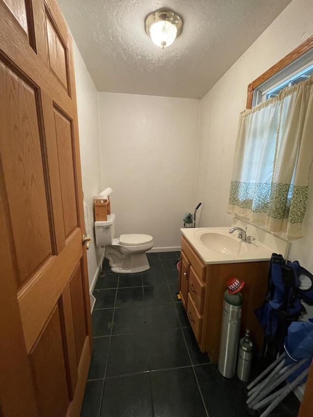 bathroom with toilet, a textured ceiling, vanity, and tile patterned floors