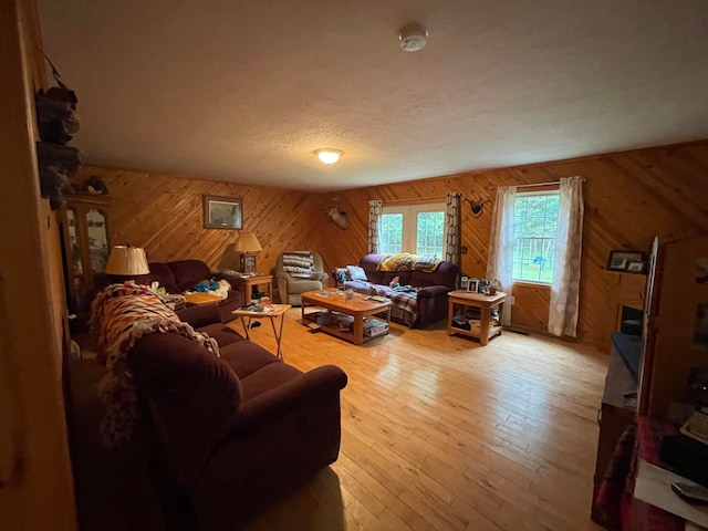 living room with wood walls, light hardwood / wood-style floors, and a textured ceiling