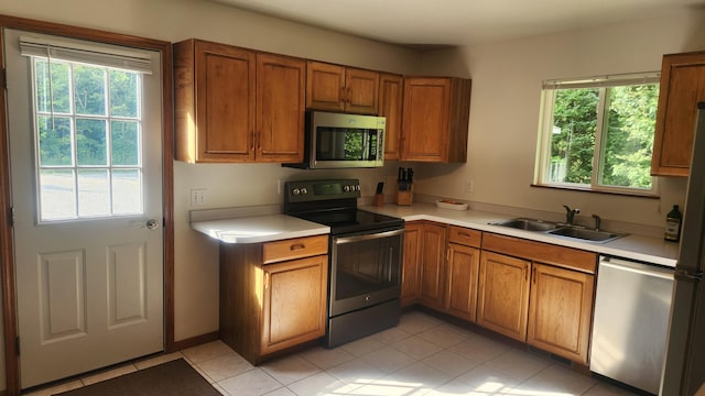 kitchen featuring a healthy amount of sunlight, stainless steel appliances, light tile patterned flooring, and sink