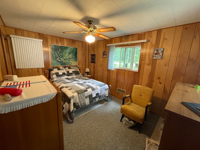 bedroom featuring wood walls, ceiling fan, and carpet floors