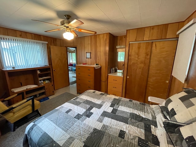 bedroom with wood walls, ceiling fan, and carpet floors