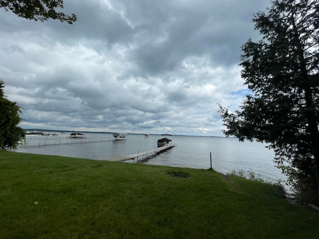 view of dock with a water view and a yard