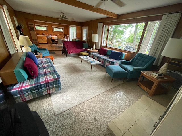 living room featuring carpet, beamed ceiling, ceiling fan, and wooden walls