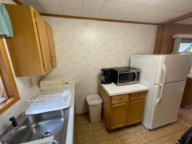 kitchen with crown molding, sink, and white refrigerator