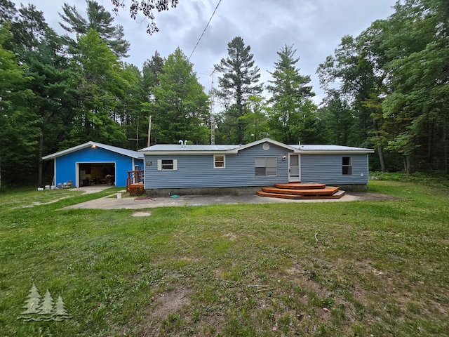 rear view of property with an outdoor structure, a garage, and a lawn