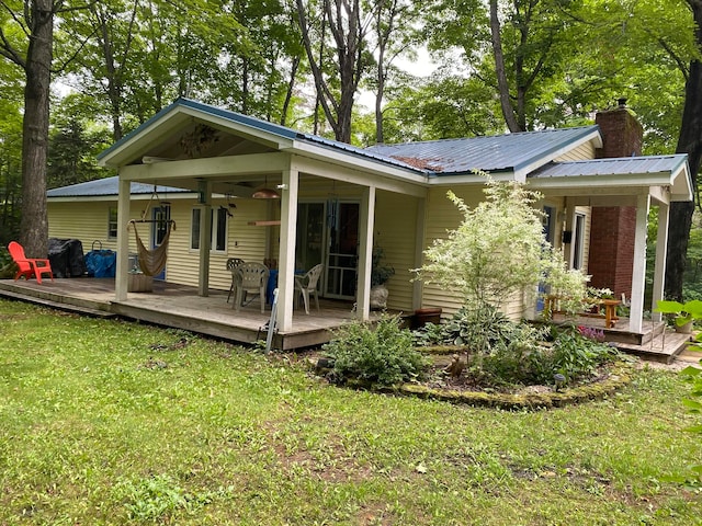 rear view of property with a yard, ceiling fan, and a deck