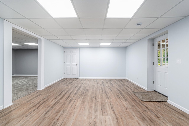 basement featuring a paneled ceiling and hardwood / wood-style flooring