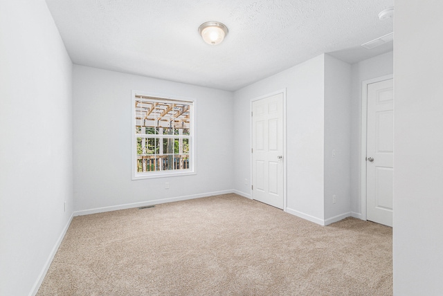 unfurnished bedroom featuring a textured ceiling, a closet, and light carpet