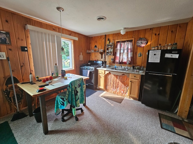 kitchen with black refrigerator, decorative light fixtures, carpet floors, and gas stove