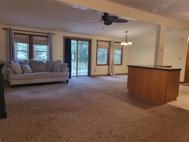 carpeted living room featuring ceiling fan with notable chandelier and a textured ceiling