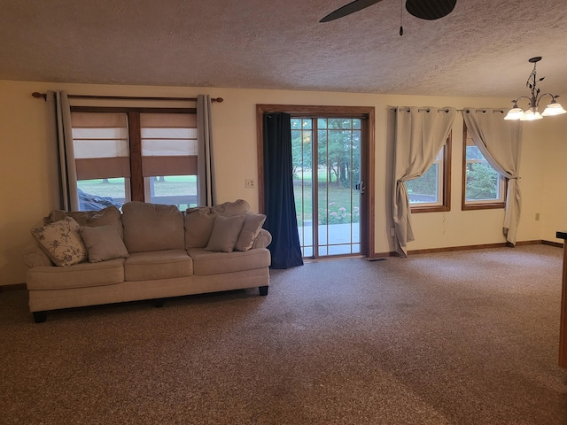 unfurnished living room featuring carpet, ceiling fan with notable chandelier, and a textured ceiling