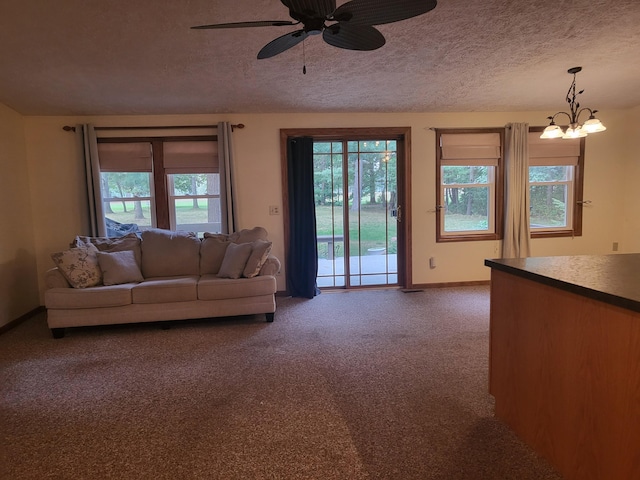 living room featuring a textured ceiling, ceiling fan with notable chandelier, and dark colored carpet