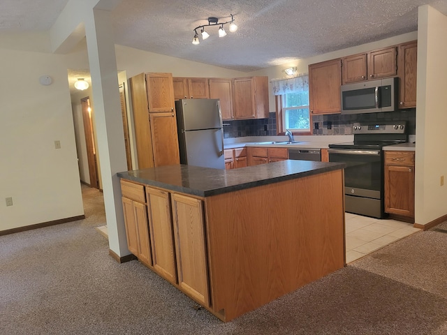 kitchen with decorative backsplash, appliances with stainless steel finishes, light colored carpet, vaulted ceiling, and a kitchen island