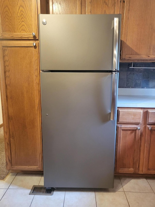 kitchen featuring stainless steel fridge, tasteful backsplash, and light tile patterned floors