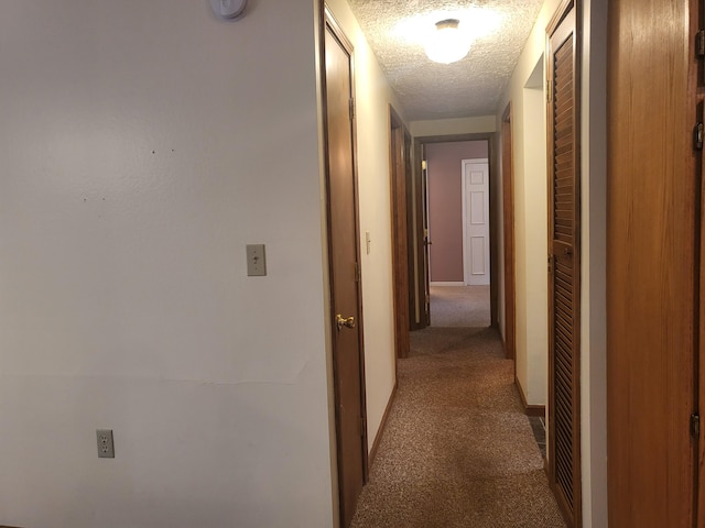 hallway with light carpet and a textured ceiling