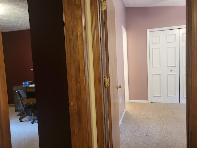 hall featuring carpet flooring and a textured ceiling