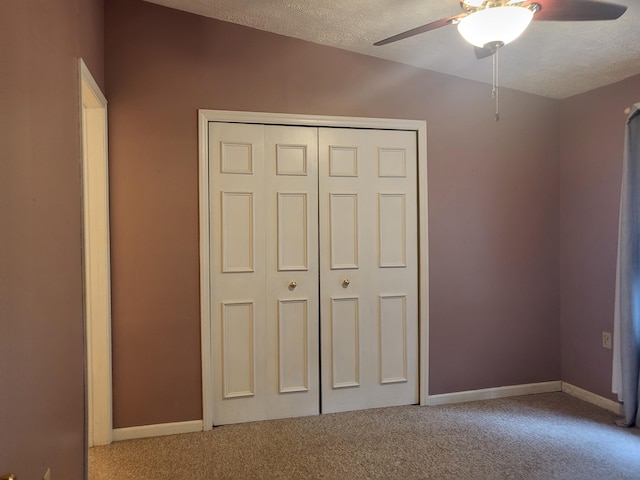 unfurnished bedroom featuring ceiling fan, a closet, carpet floors, and a textured ceiling