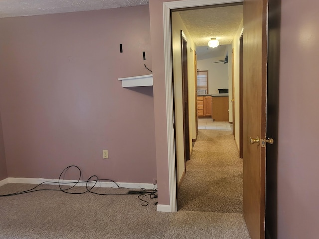 corridor featuring light carpet and a textured ceiling