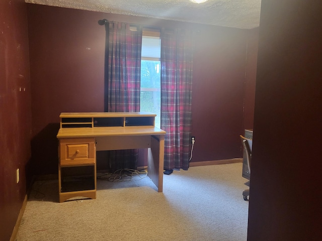 carpeted office featuring a textured ceiling