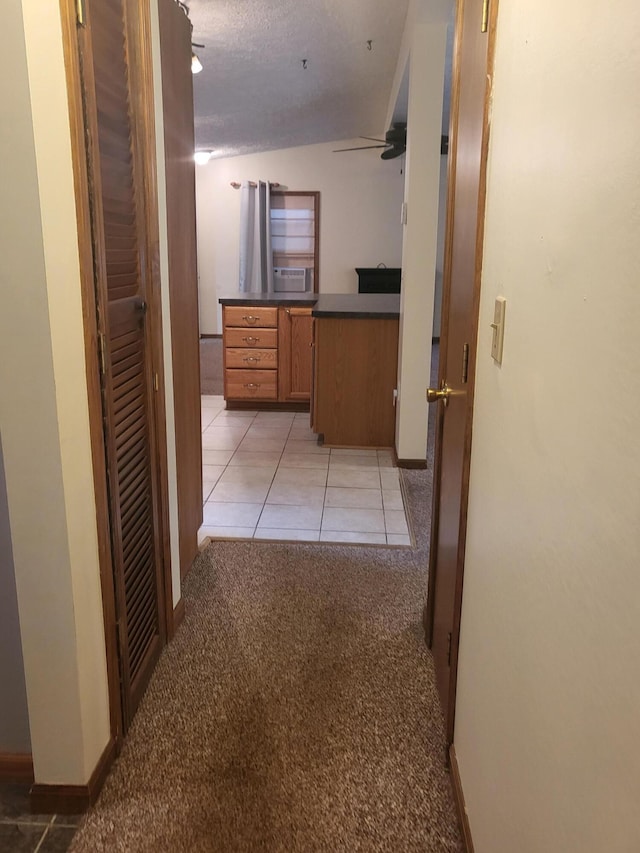 hallway with light carpet and a textured ceiling