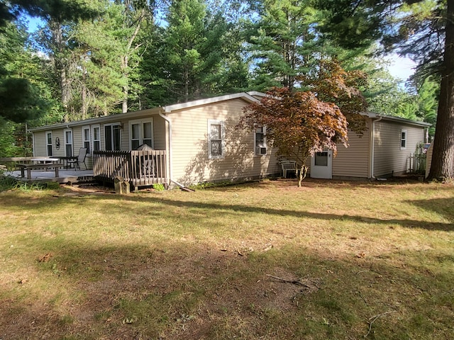 back of property with a lawn and a wooden deck