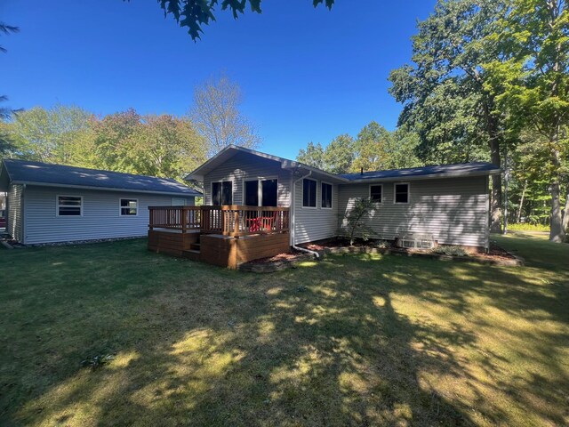 rear view of property featuring a wooden deck and a lawn