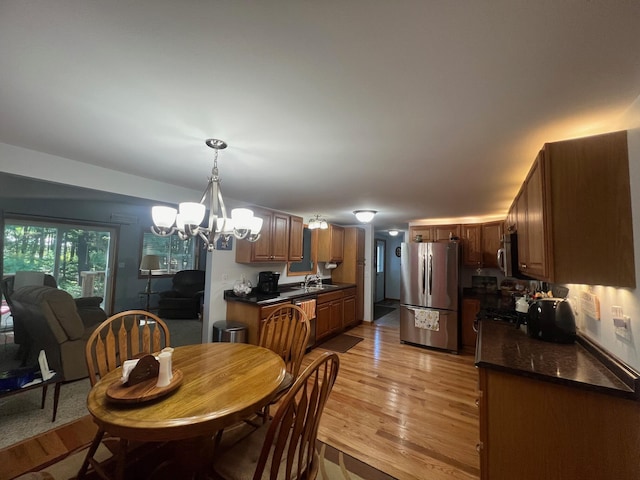 dining space featuring sink, a chandelier, and light hardwood / wood-style floors