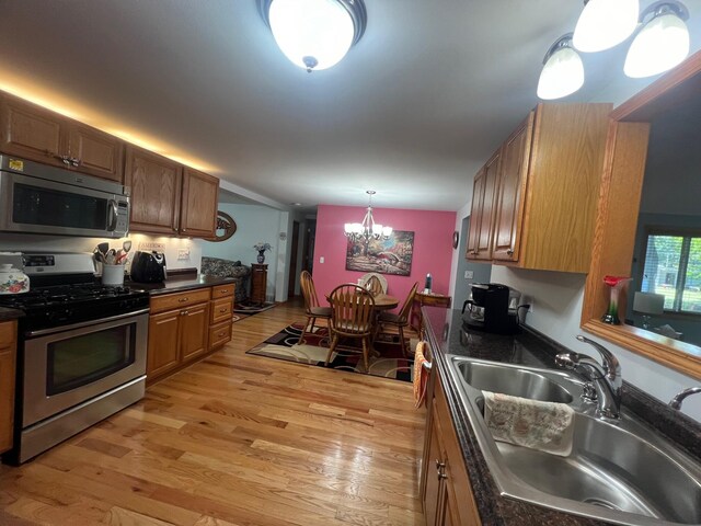 kitchen featuring hanging light fixtures, light hardwood / wood-style flooring, stainless steel appliances, a notable chandelier, and sink