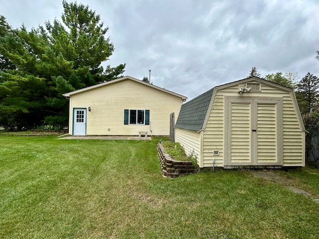 rear view of property featuring a yard and a storage unit